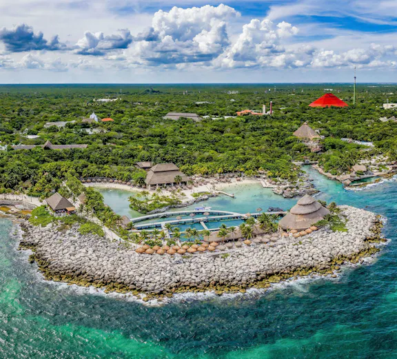 Aerial view of Xcaret Park's coastline with lush greenery and turquoise waters in Mexico.