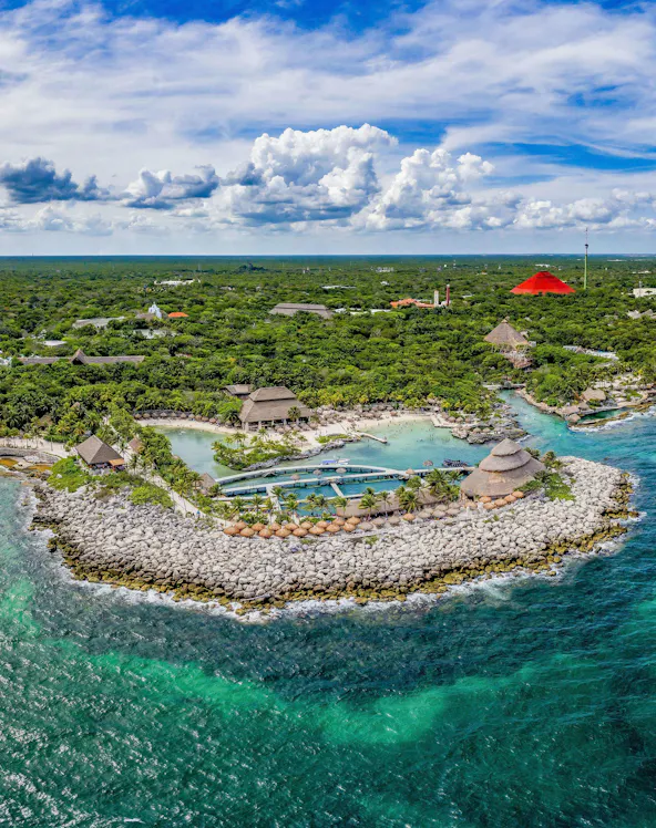 Aerial view of Xcaret Park's coastline with lush greenery and turquoise waters in Mexico.
