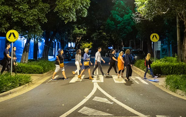 Group walking on a crosswalk during Sydney's Razor Gang True Crime Tour at night.