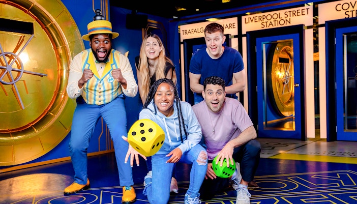 Guests playing a life-sized Monopoly game in London, interacting with oversized game pieces.