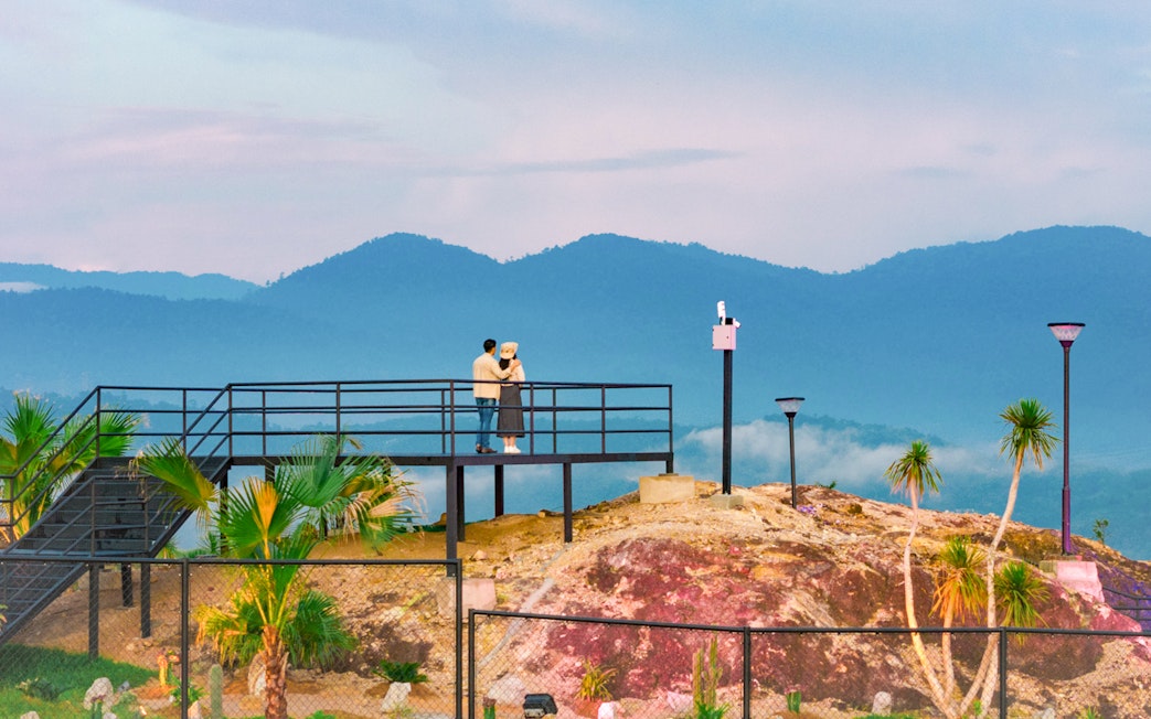 Couple on viewing platform overlooking Dino Desert landscape.