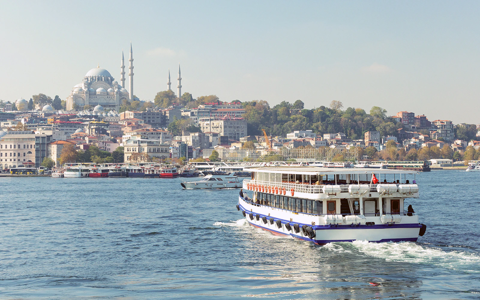 Sightseeing cruise on the Bosphorus with Istanbul skyline and mosque in the background.