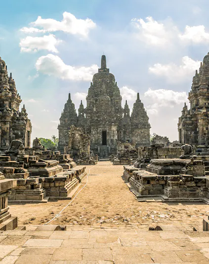 Prambanan Temple complex with ancient stone structures under a blue sky in Yogyakarta, Indonesia.