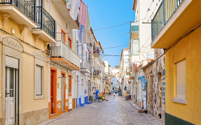 Narrow cobblestone street with colorful buildings in Nazare, Portugal.