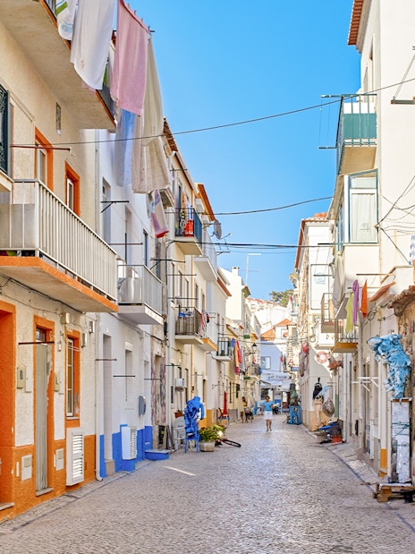 Narrow cobblestone street with colorful buildings in Nazare, Portugal.