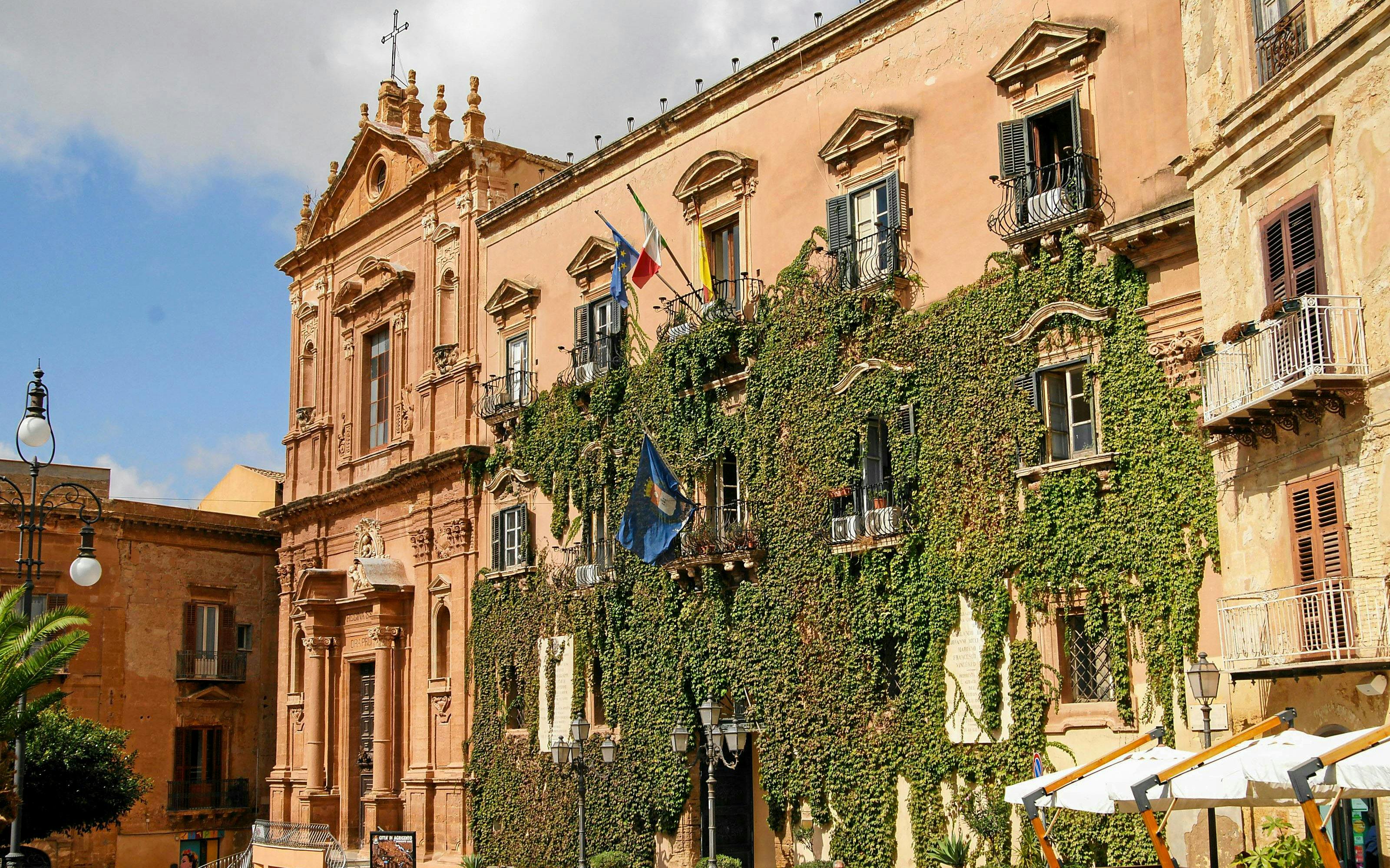 Historic building with ivy-covered facade in Piazza Luigi Pirandello, Agrigento, Italy.