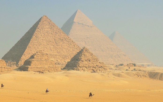 Pyramids of Giza with camels in the foreground, Egypt desert landscape.