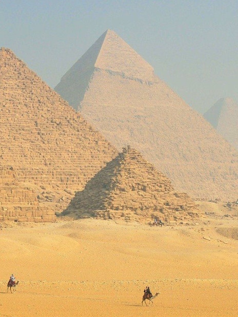 Pyramids of Giza with camels in the foreground, Egypt desert landscape.