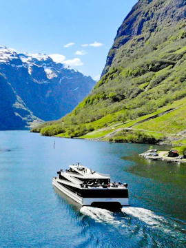 Cruise ship sailing through Nærøyfjord with mountains in the background, Norway.