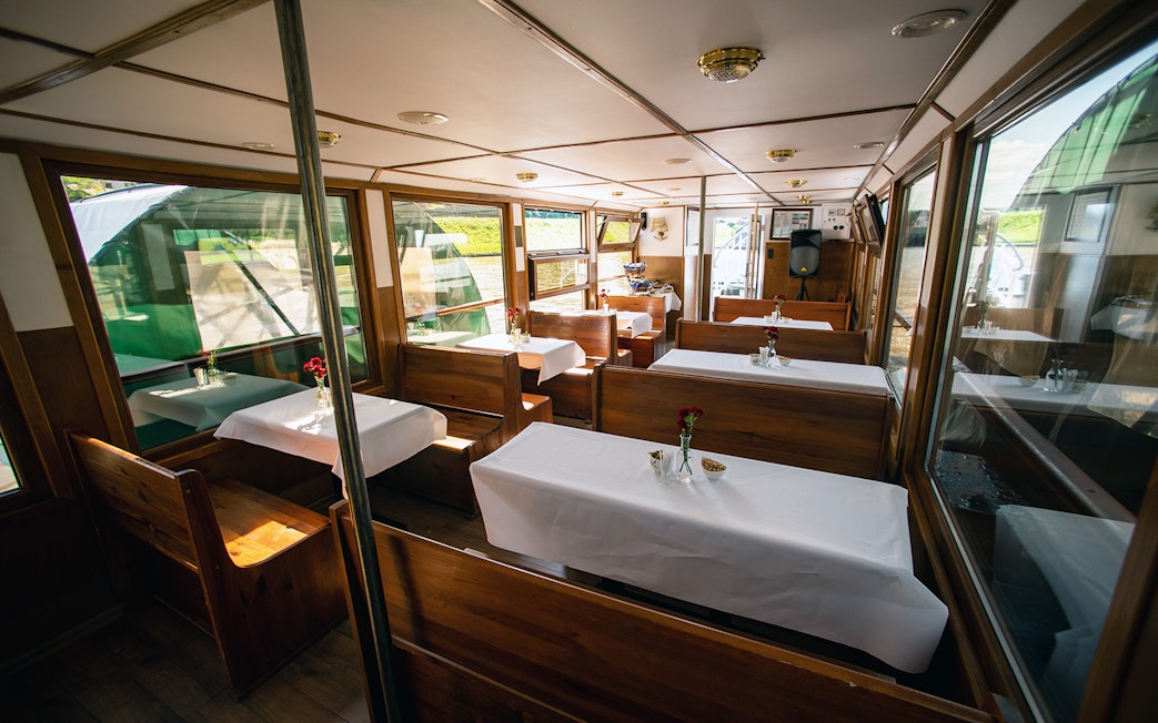 Interior of a Vistula River sightseeing cruise boat with tables set for a Chopin piano concert.
