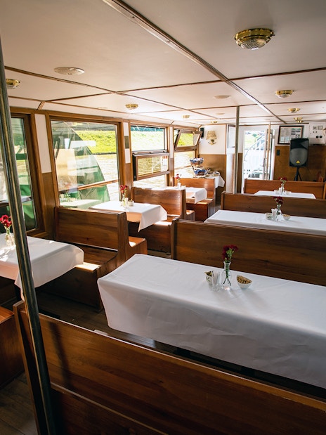 Interior of a Vistula River sightseeing cruise boat with tables set for a Chopin piano concert.