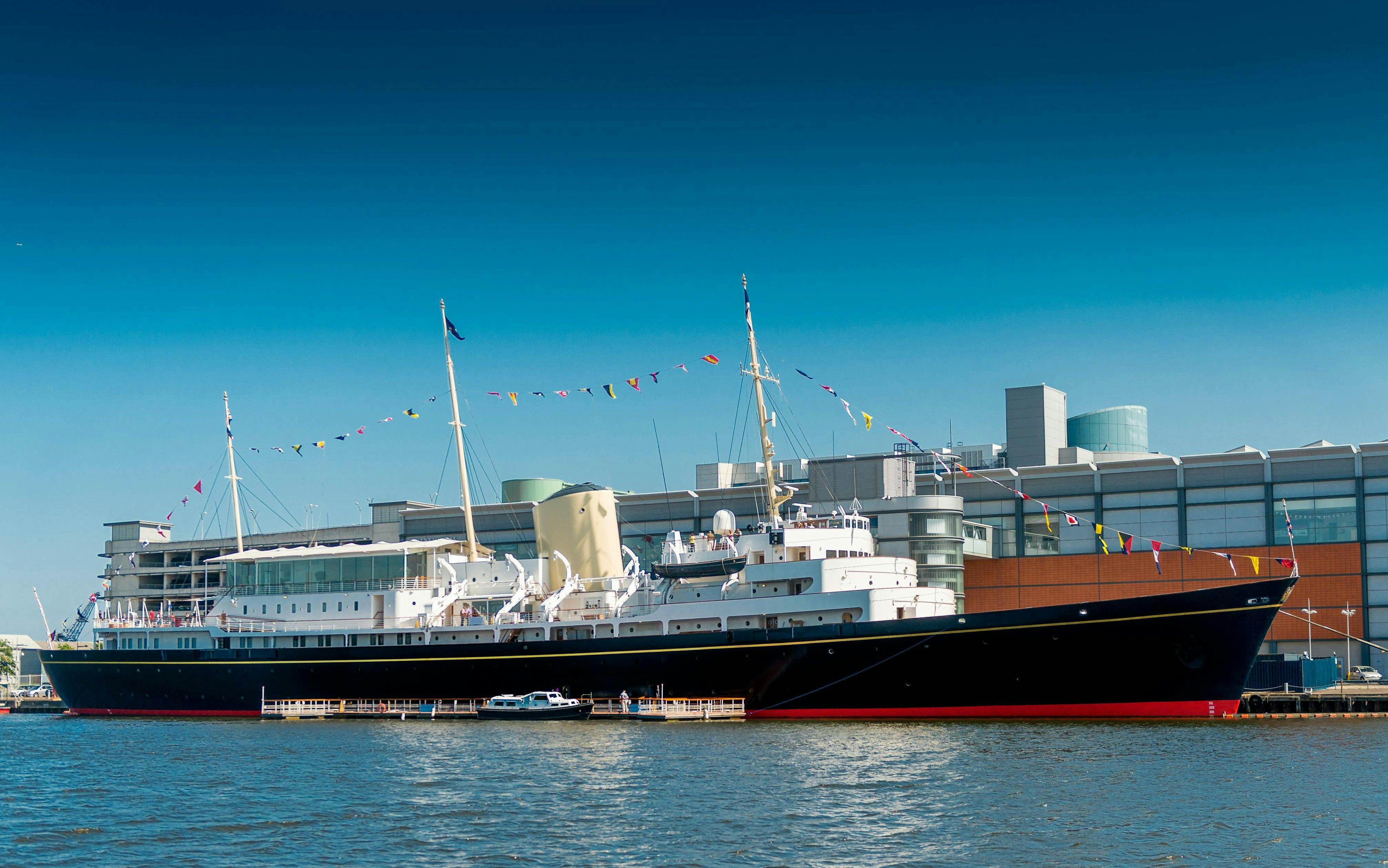 Royal Yacht Britannia docked in Edinburgh with colorful flags.