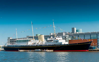 Royal Yacht Britannia docked in Edinburgh with colorful flags.