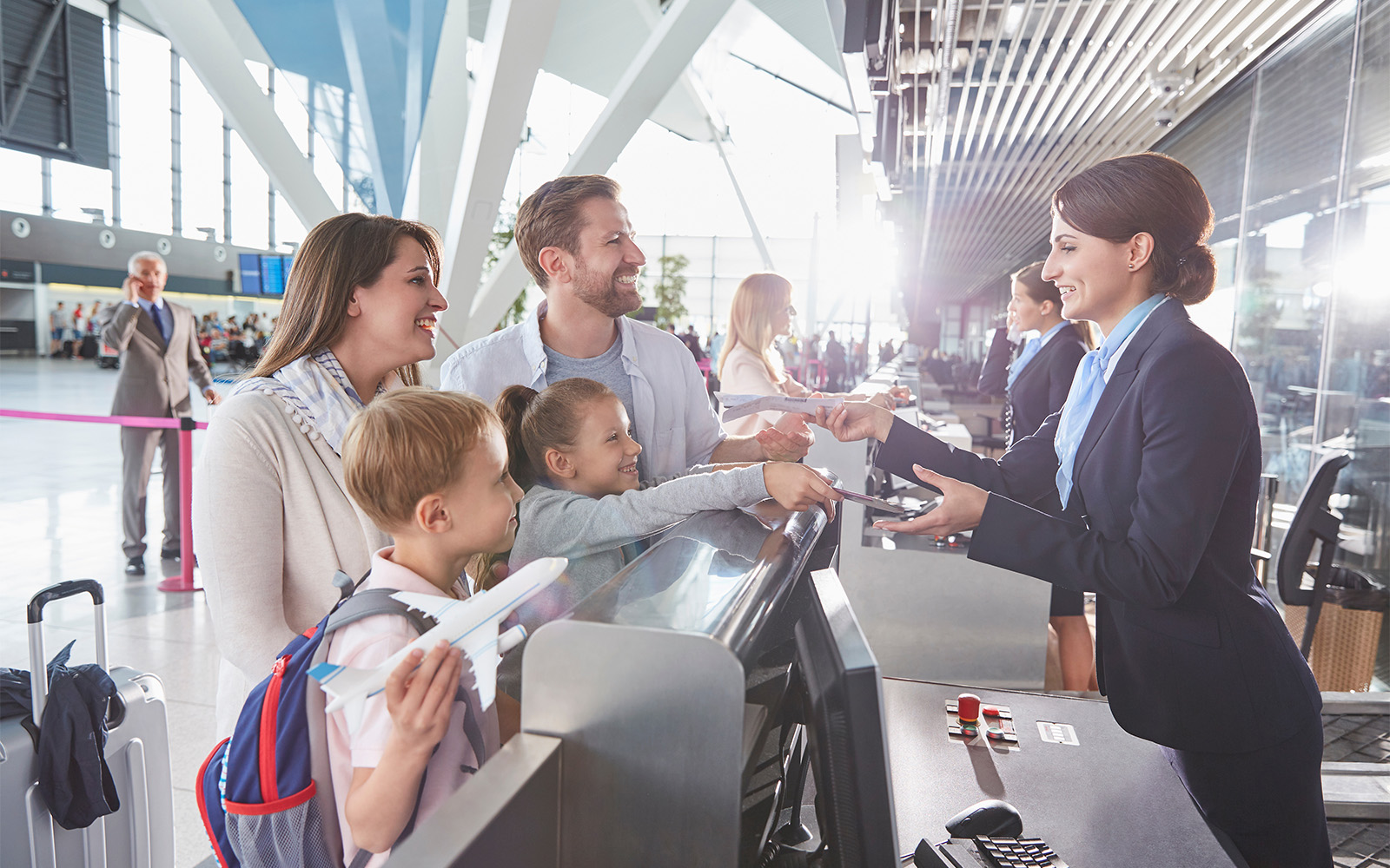 Family checking in at Rome airport counter, smiling and handing over passports.