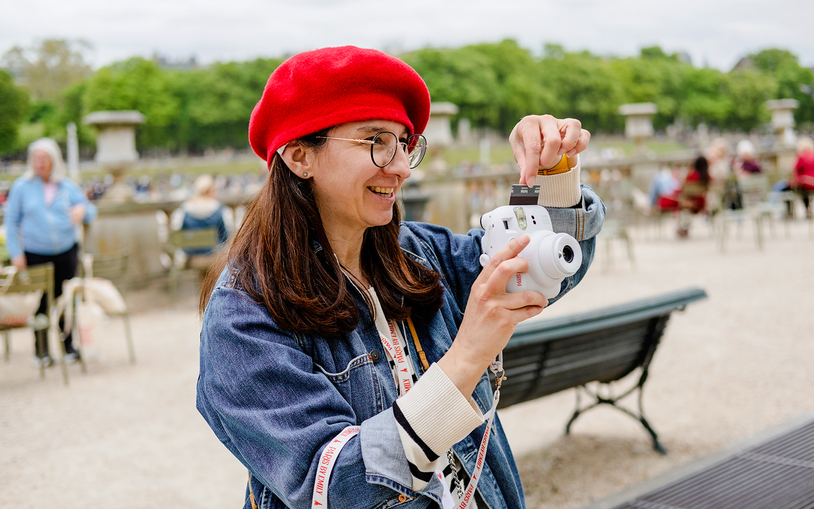 Person taking a polaroid during Emily in Paris Food Tour in a park setting.