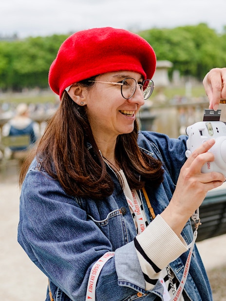 Person taking a polaroid during Emily in Paris Food Tour in a park setting.