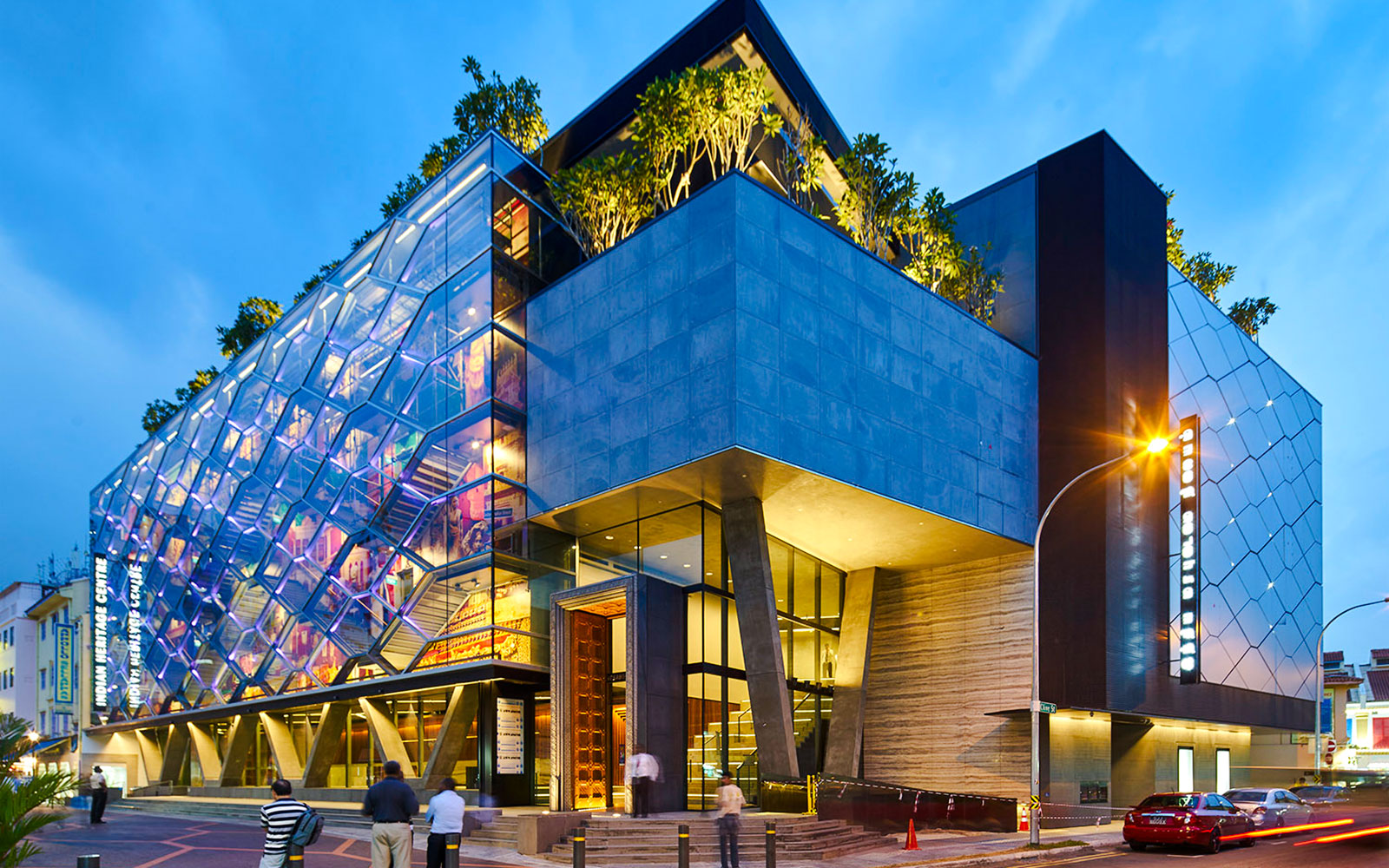 Indian Heritage Centre in Singapore with illuminated colorful glass facade at dusk.