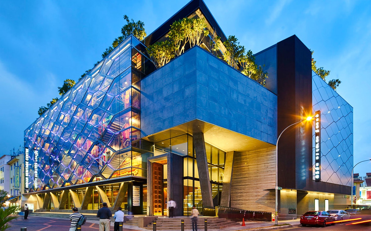 Indian Heritage Centre in Singapore with illuminated colorful glass facade at dusk.
