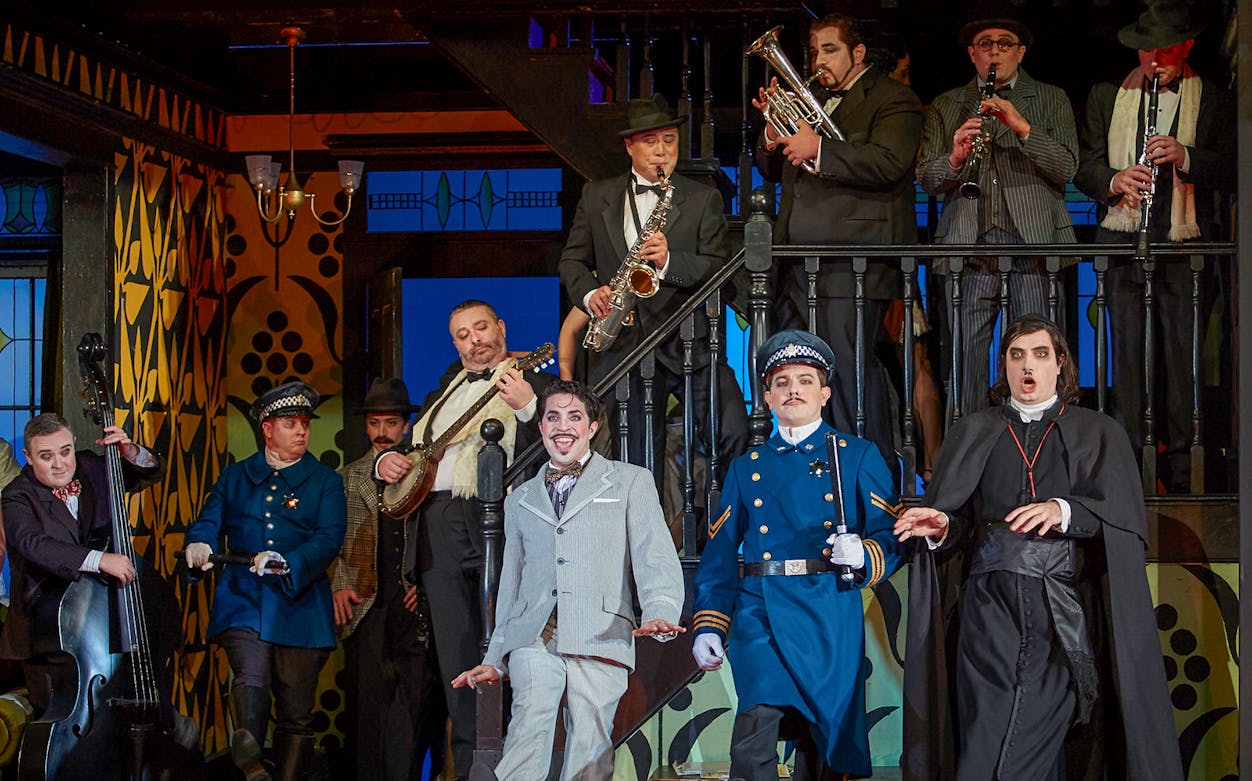 Performers in a lively scene from "The Barber of Seville" opera, featuring musicians and actors in period costumes.