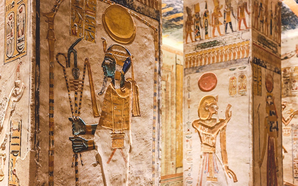 Ancient Egyptian hieroglyphs and deities on tomb walls in the Valley of the Kings, Luxor, Egypt.