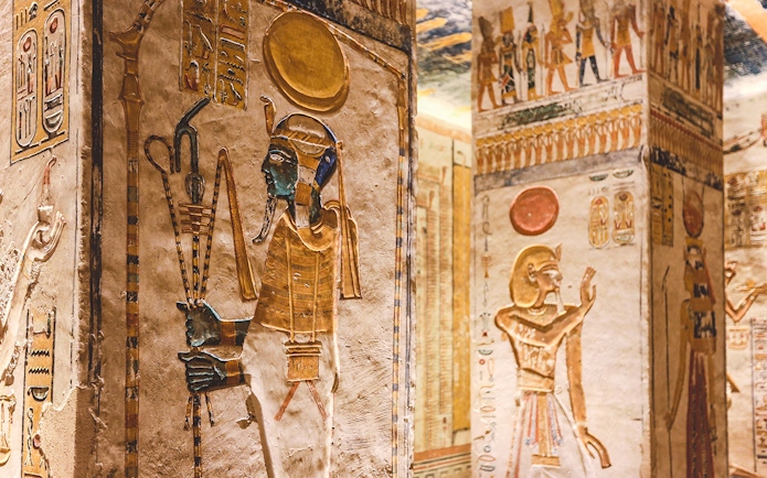 Ancient Egyptian hieroglyphs and deities on tomb walls in the Valley of the Kings, Luxor, Egypt.