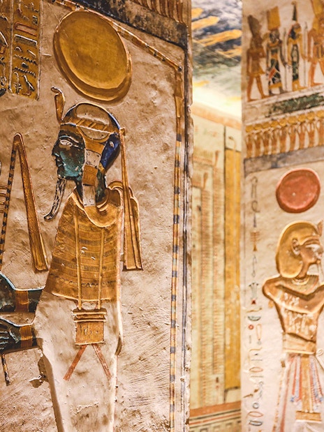 Ancient Egyptian hieroglyphs and deities on tomb walls in the Valley of the Kings, Luxor, Egypt.