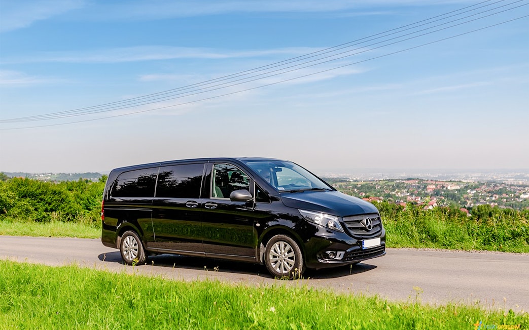 Black van on a scenic road, used for Auschwitz Birkenau AC transfer.