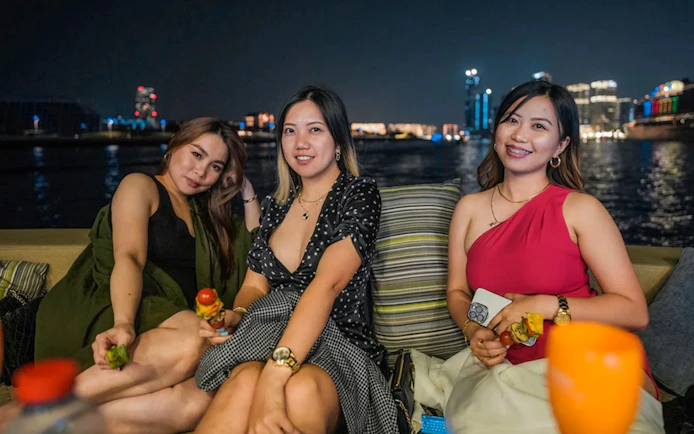 Ladies enjoying BBQ on a Dubai Marina yacht party at night.