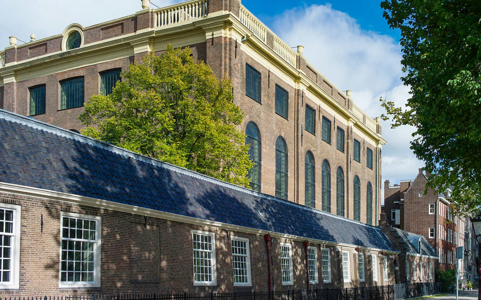 Exteriors of the Portuguese Synagogue in Amsterdam with brick facade and arched windows.