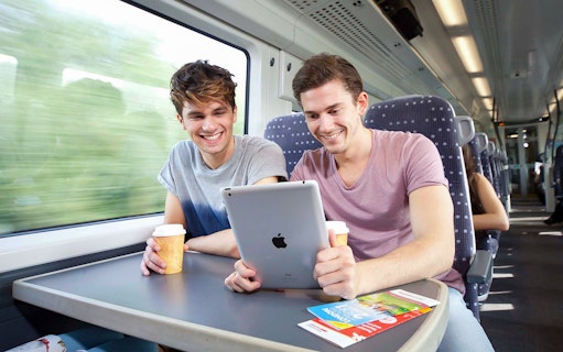 Passengers enjoying a tablet and coffee on the Stansted Express train to Stratford.