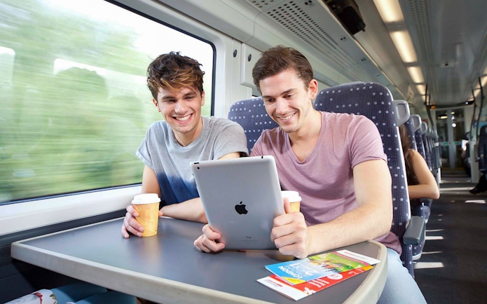 Passengers enjoying a tablet and coffee on the Stansted Express train to Stratford.