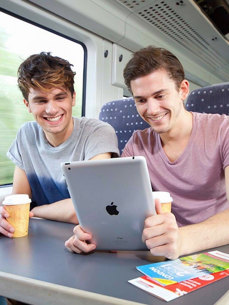 Passengers enjoying a tablet and coffee on the Stansted Express train to Stratford.