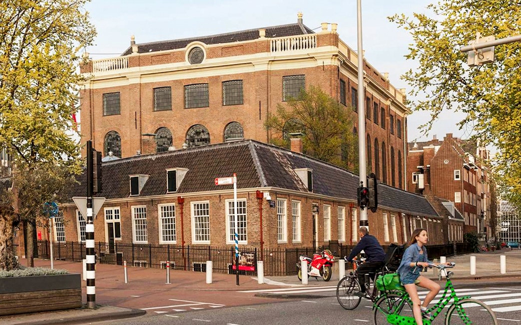 Jewish Museum and Synagogue in Amsterdam with cyclists passing by.