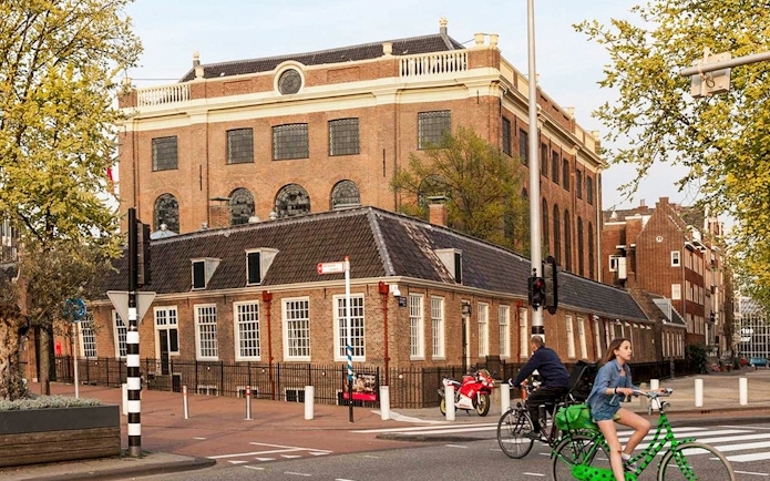 Jewish Museum and Synagogue in Amsterdam with cyclists passing by.