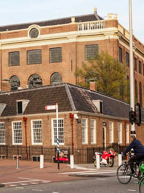Jewish Museum and Synagogue in Amsterdam with cyclists passing by.