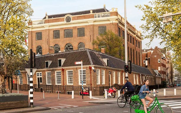 Jewish Museum and Synagogue in Amsterdam with cyclists passing by.