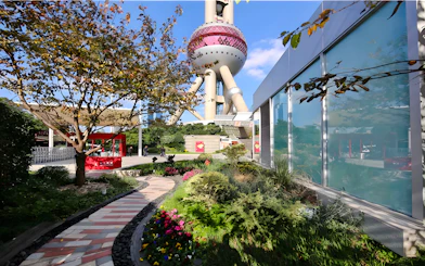 Ground floor view of Oriental Pearl Tower, Shanghai, with garden path and modern architecture.