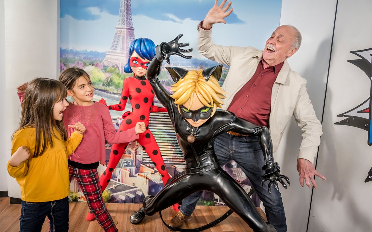 Visitors posing with Ladybug and Cat Noir figures at Grevin Museum, Paris.