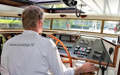 Captain steering a boat on an Amsterdam canal cruise.