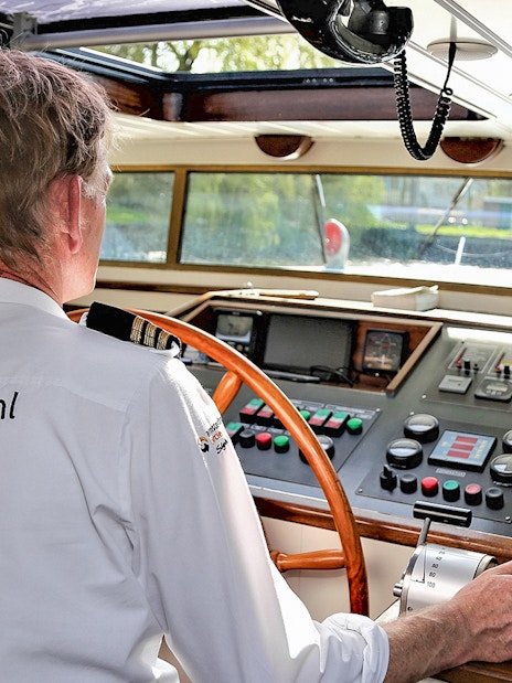 Captain steering a boat on an Amsterdam canal cruise.