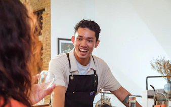Bartender engaging with guest during coffee-themed cocktail experience in Vietnam.