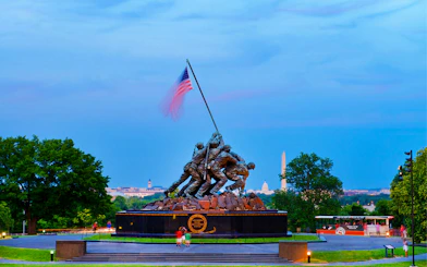 US Marine Corps War Memorial at dusk with Washington Monument in background.