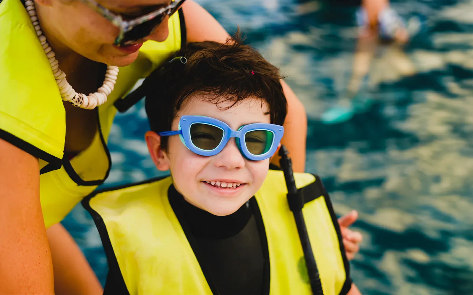 Child wearing a life jacket and sunglasses on Kaula Kai Snorkel Sail, Oahu.