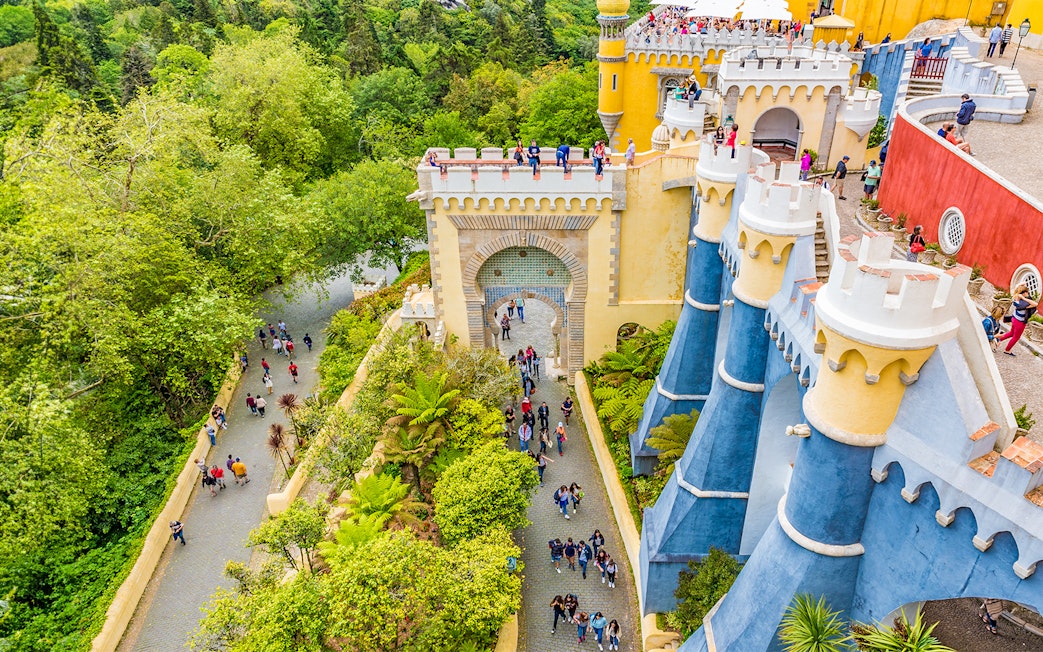 Visitors exploring the colorful architecture of Pena Palace, Sintra, Portugal.