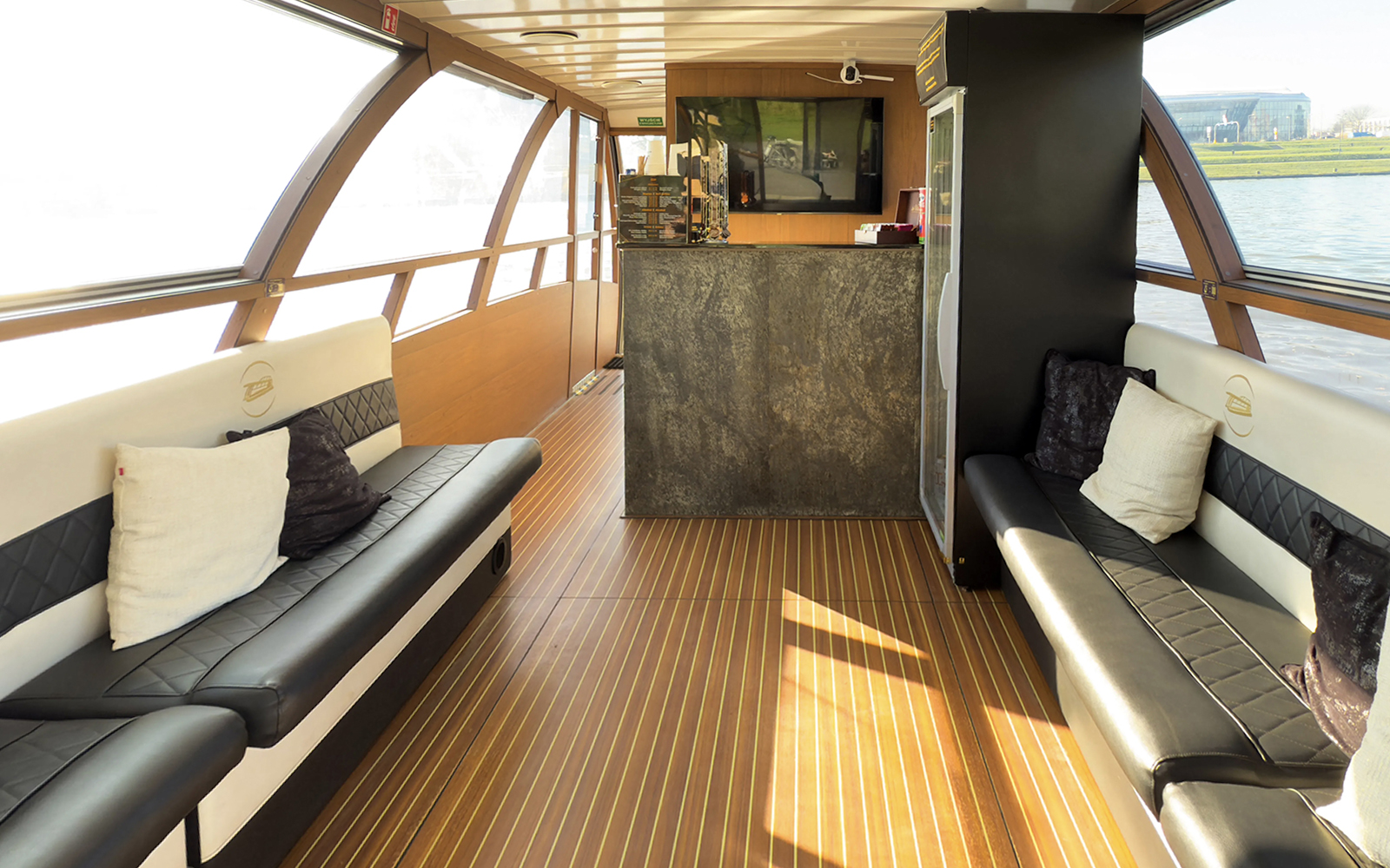 Interior seating area of Vistula River Cruise boat with large windows and a bar.