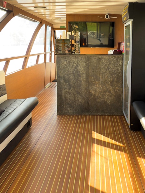 Interior seating area of Vistula River Cruise boat with large windows and a bar.