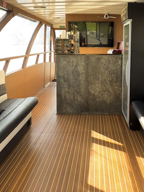 Interior seating area of Vistula River Cruise boat with large windows and a bar.