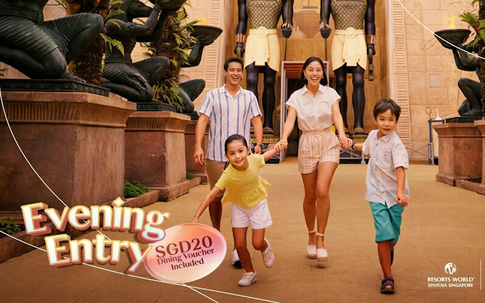 Family enjoying evening entry at Resorts World Sentosa with ancient Egyptian statues.