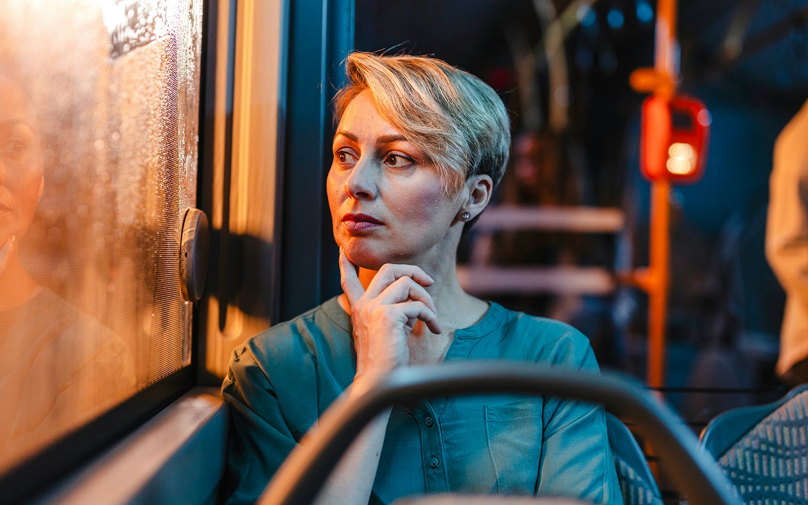 Passenger looking out window during night bus tour.