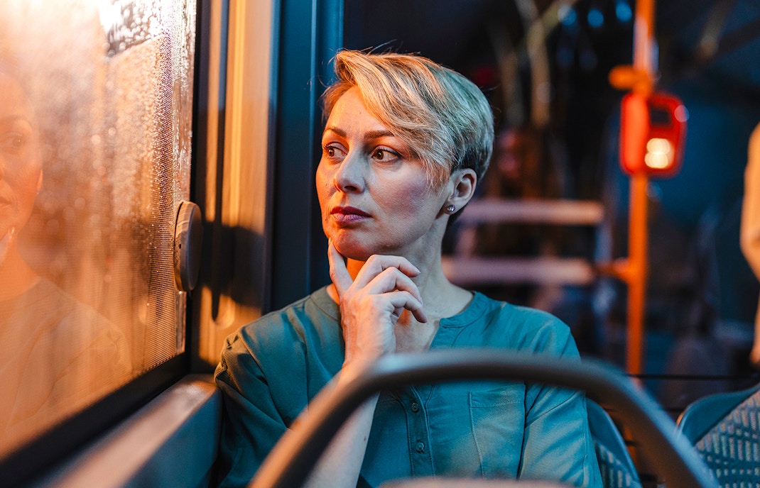 Passenger looking out window during night bus tour.
